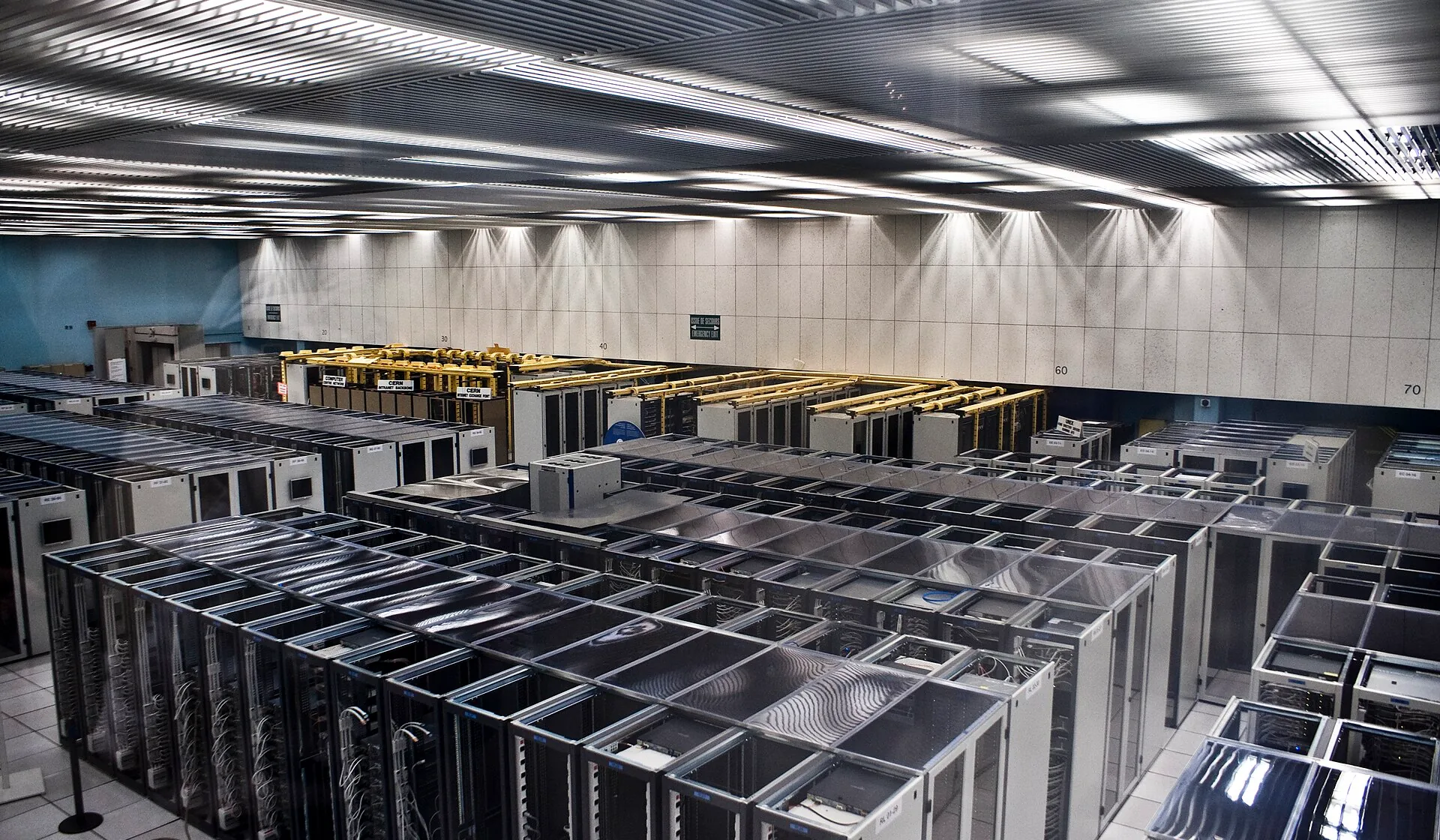 Rows of server cabinets beneath metal cable trays in the CERN computing center.