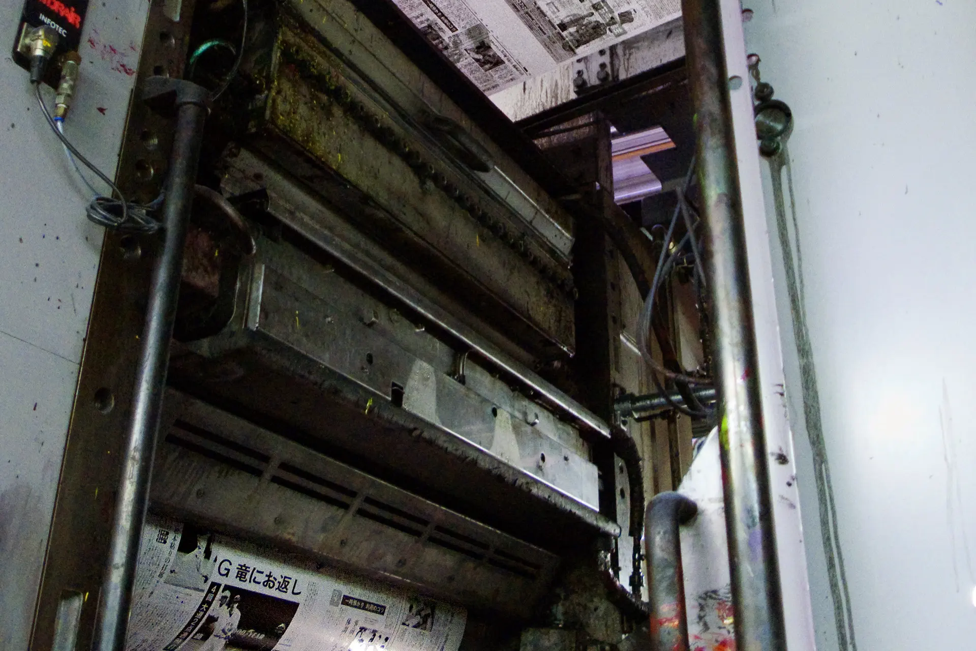 Newspaper pages passing through a web-fed offset printing press, photographed in 2009. Contextual image, not a photograph of the companies in the 2018 merger example.